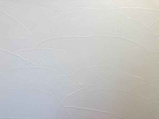 白の漆喰の壁の写真。こてのあとを模様としてあえて残した、おしゃれな雰囲気の壁になっている。